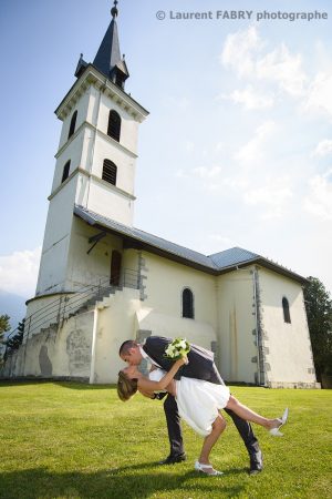 mariés photographiés devant une église pour leur mariage à Saint-Vital