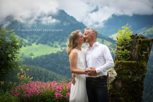 Baiser des mariés devant un décor de montagne fleuri au printemps (Beaufortain, Savoie) : mariage dans les Alpes