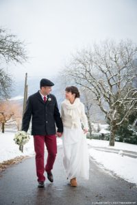 Les mariés se donnent la main, habillés en vêtements d'hiver pour ce mariage photographié en décembre près d'Annecy
