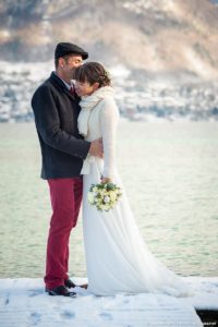 Les mariés posent sur le ponton enneigé du lac d'Annecy (mariage en hiver)