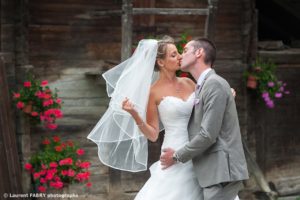 Photo des mariés devant un grenier fleuri en Savoie, photographe de mariage dans le val d