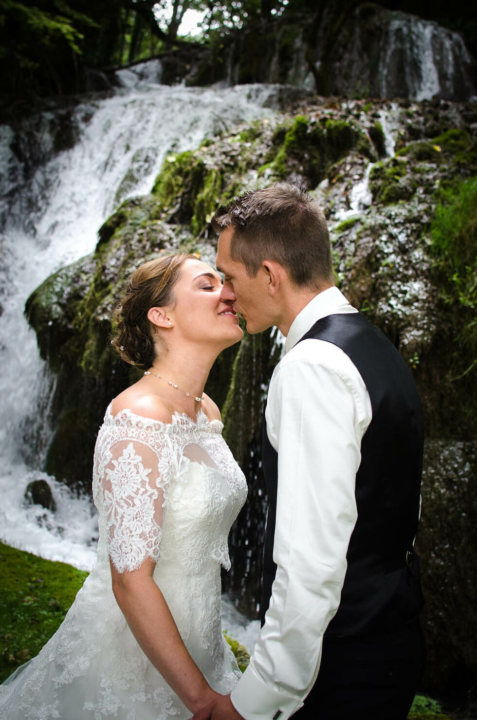 baiser des mariés devant la cascade, photographe de mariage en Savoie