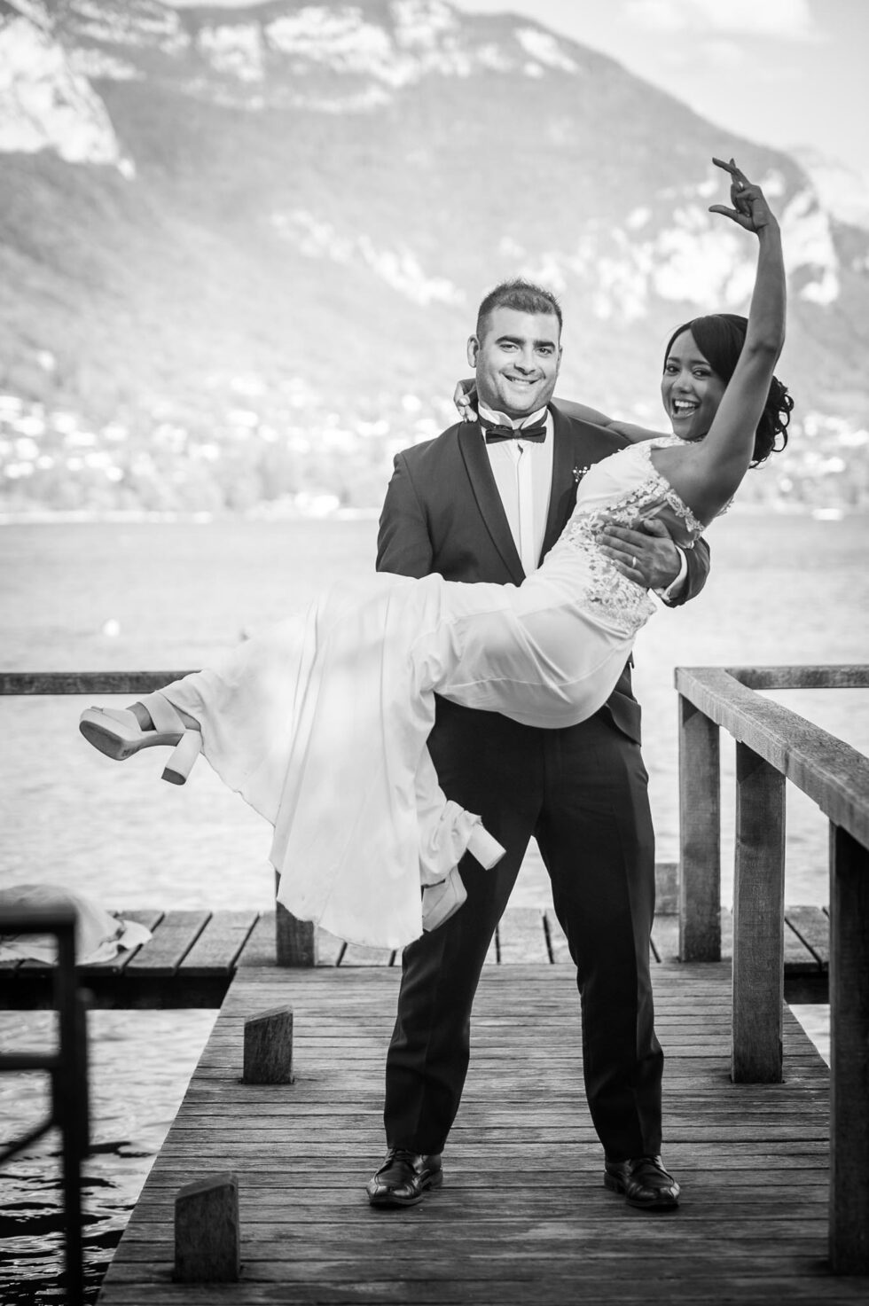 Photographe de mariage à Annecy : pose romantique des mariés sur le ponton de l'Imperial Palace, en noir et blanc