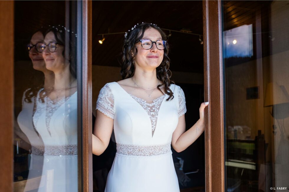 Reportage de mariage en automne à la montagne : la mariée souriante se prépare