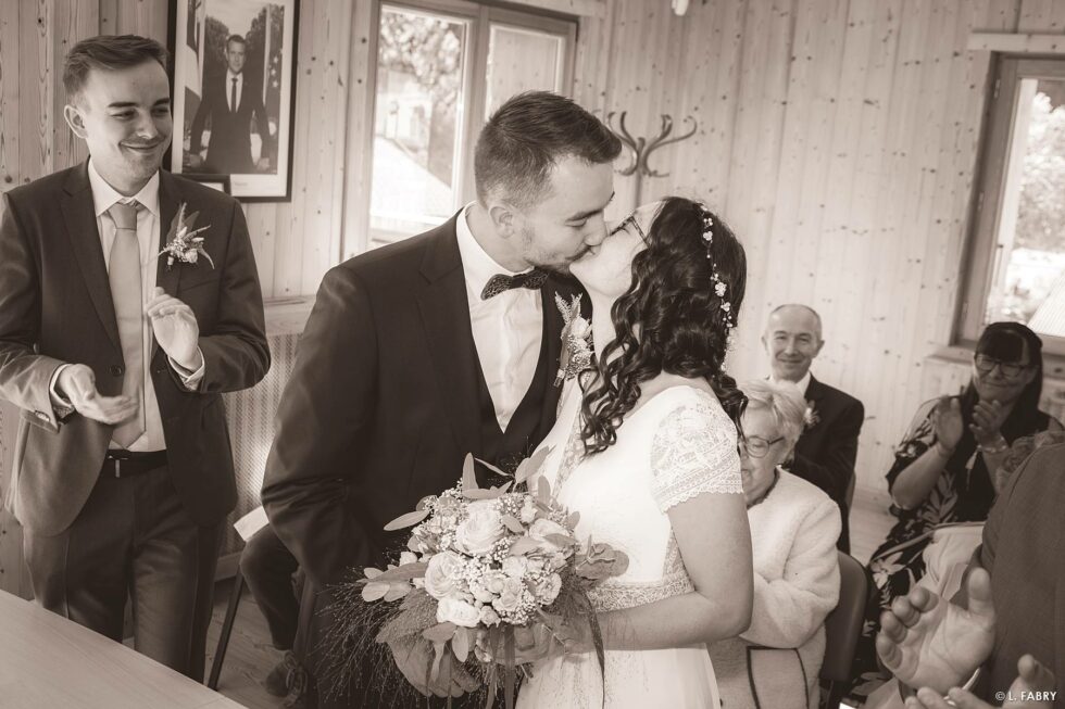 Reportage de mariage en automne à la montagne : les mariés s'embrassent en mairie (photographie sépia)