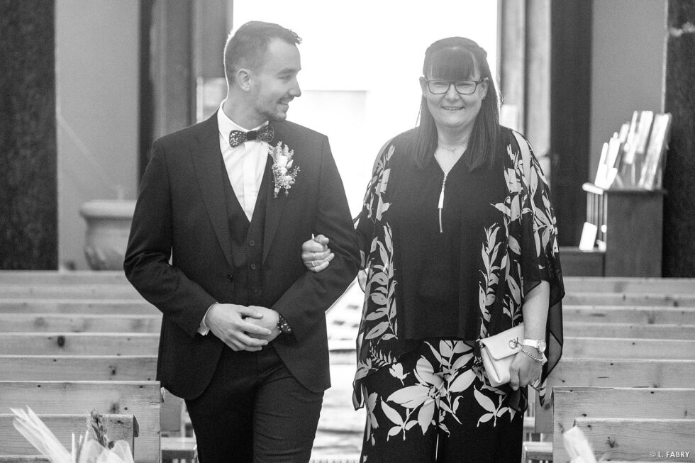 Reportage de mariage en automne à la montagne : la maman accompagne son fils dans l'église