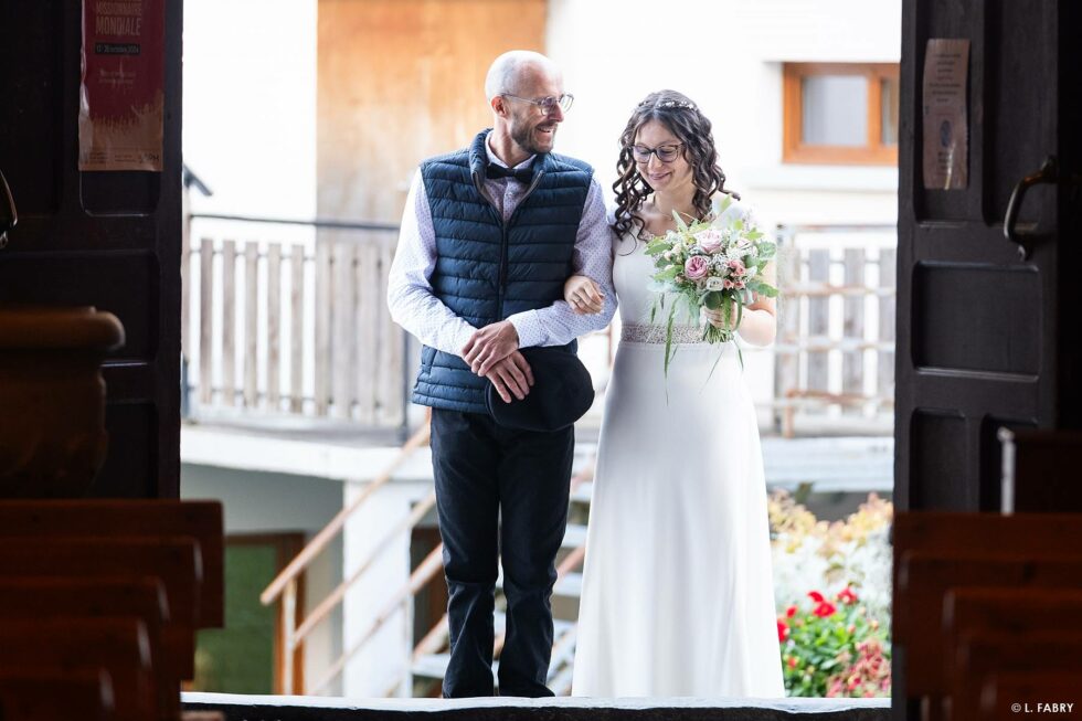 Reportage de mariage en automne à la montagne : le papa accompagne sa fille dans l'église