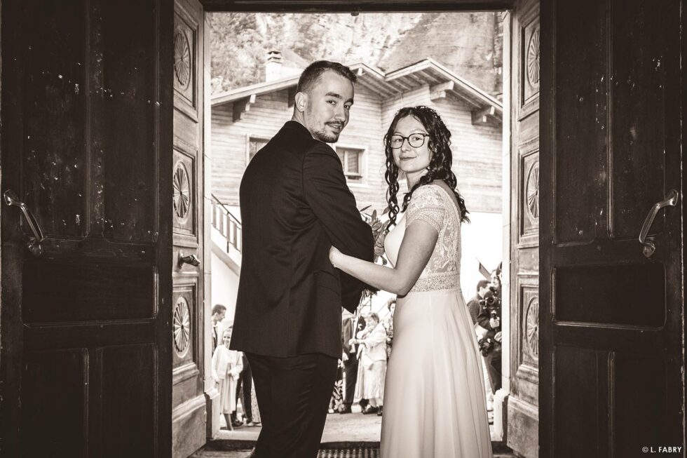 Reportage de mariage en automne à la montagne : les mariés sortent de l'église (photo sépia)