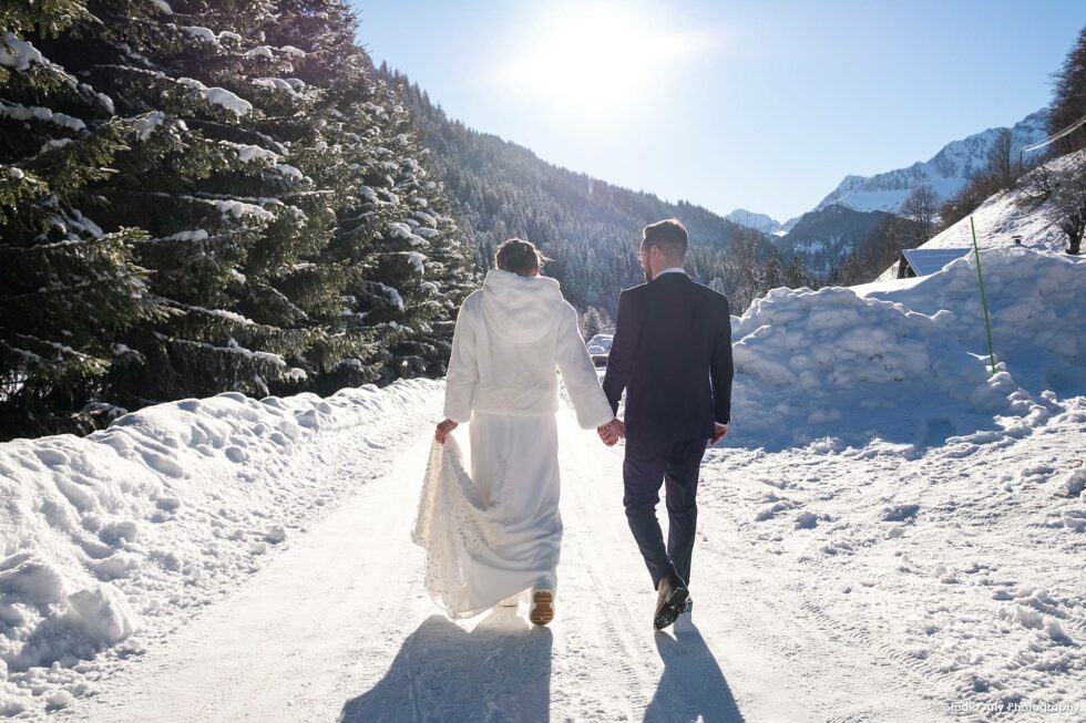 Mariage dans la neige en hiver : les mariés s'éloignent en se donnant la main