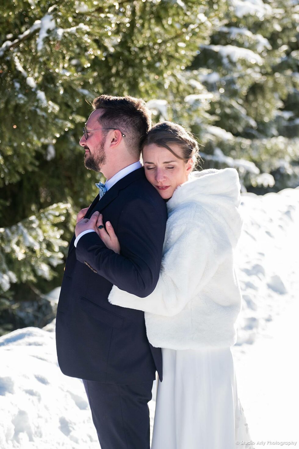 Mariage dans la neige en hiver : portrait des mariés sur fond de sapins enneigés