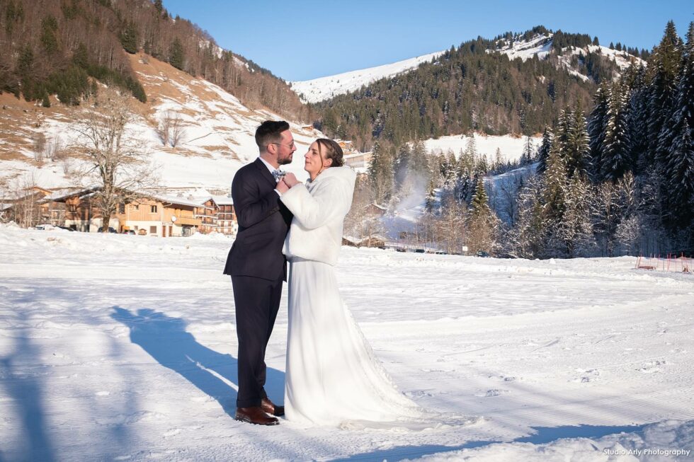Mariage dans la neige en hiver : les mariés posent au soleil sur la neige