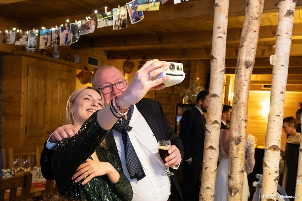 fête de mariage dans un chalet de montagne : les invités se prennent photo au Polaroïd