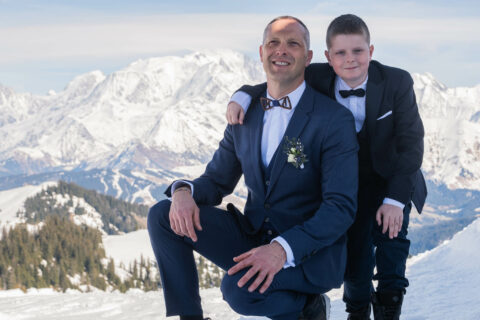 Photographe de mariage à la montagne : portrait père - fils dans la neige devant les montagnes enneigées